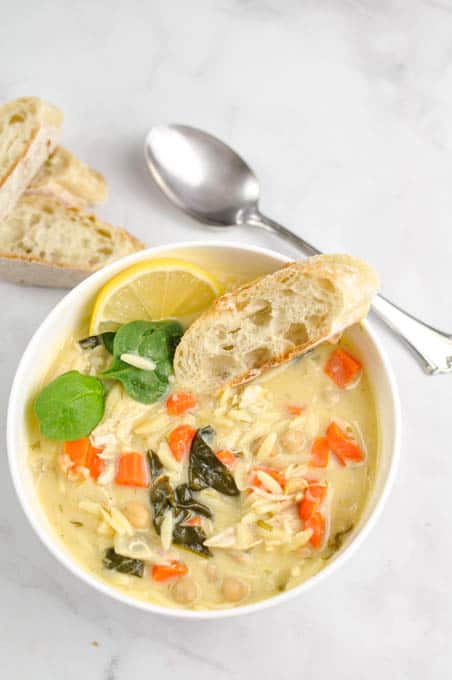 Lemon Chicken Orzo Chickpea Soup (Instant Pot cooked chicken) on white counter with a spoon and two slices of bread