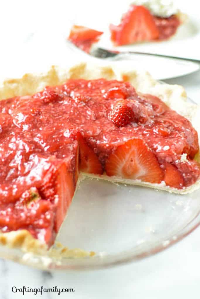 Simple fresh strawberry pie without Jello in a flaky pie crust with a slice removed showing the juicy fresh strawberry filling