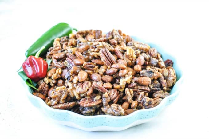 spiced nuts in a blue green bowl on a white counter. 
