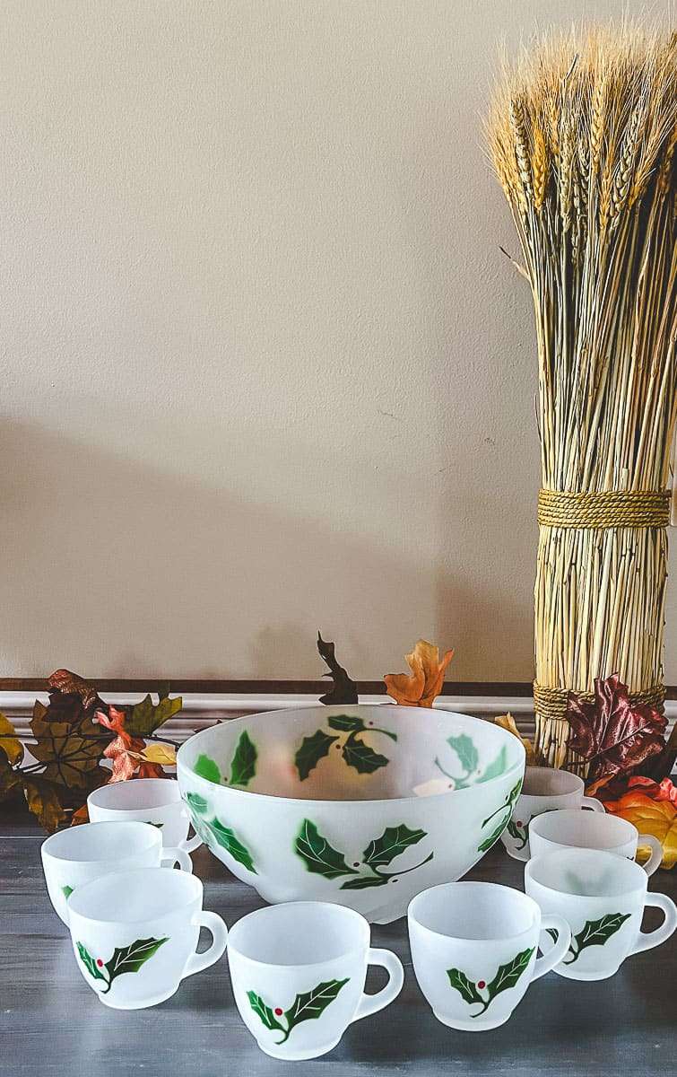 punch bowl and cups on a table with fall leaves and grass stock bundle. 