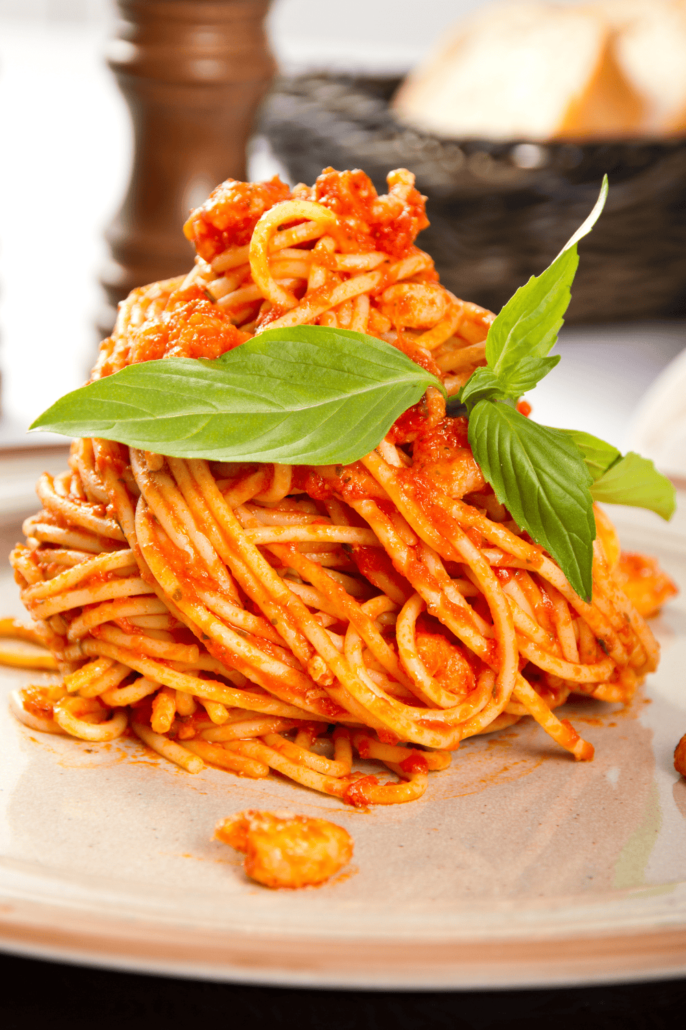 tomato sauce on pasts in a heap with 3 basil leave on top.