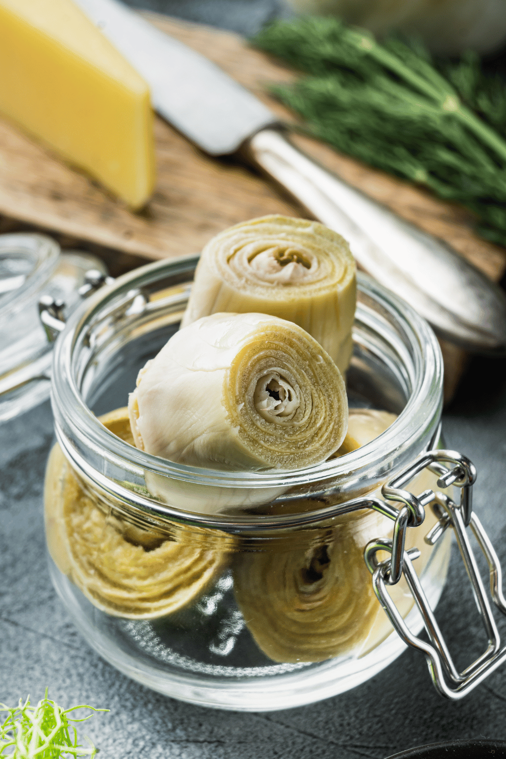 5 artichoke in a glass jar with ingredients in the background