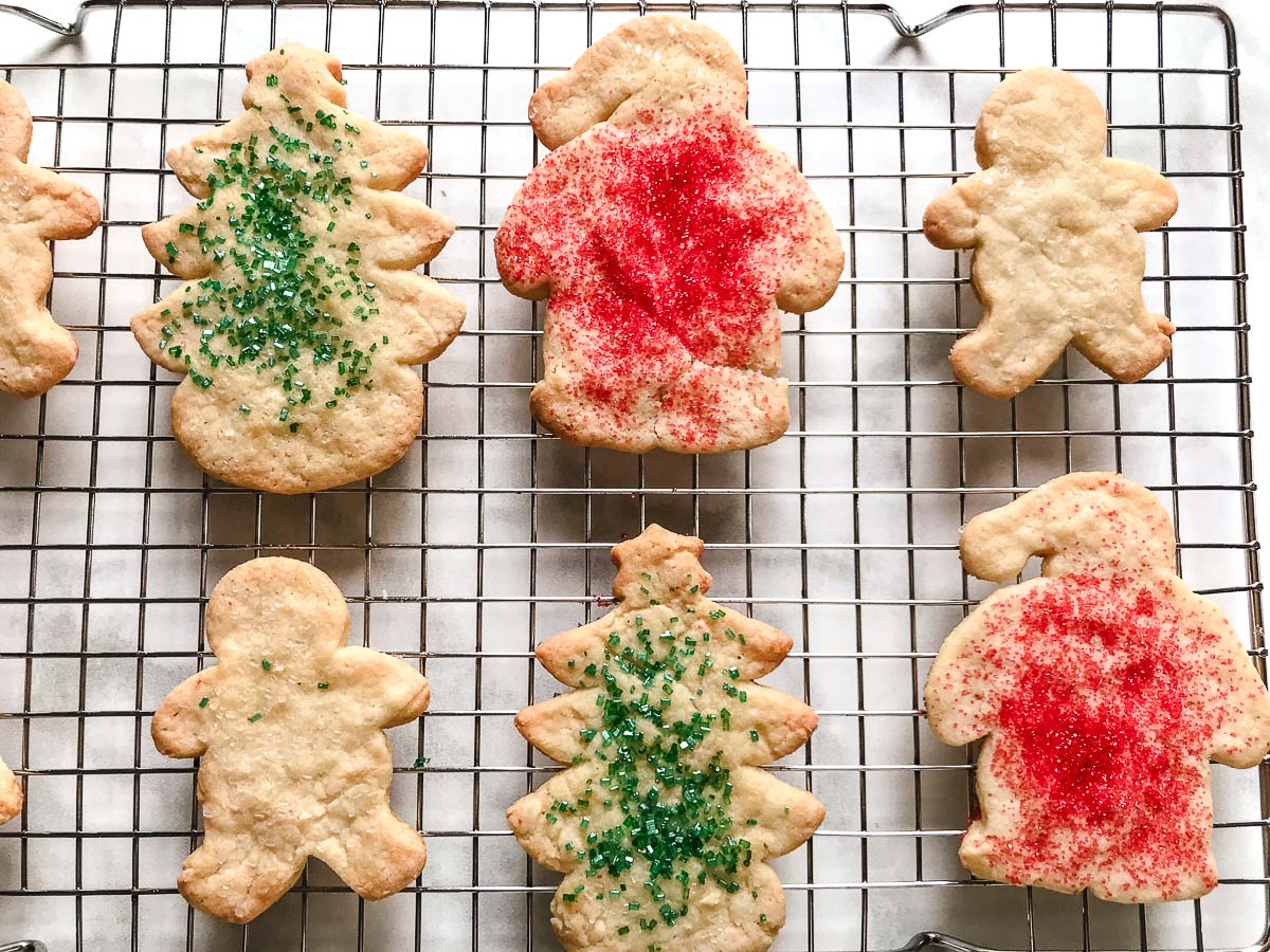 Easy cut out sugar cookie recipe, baked Christmas cookies with red and green sprinkles on a wire cooling rack