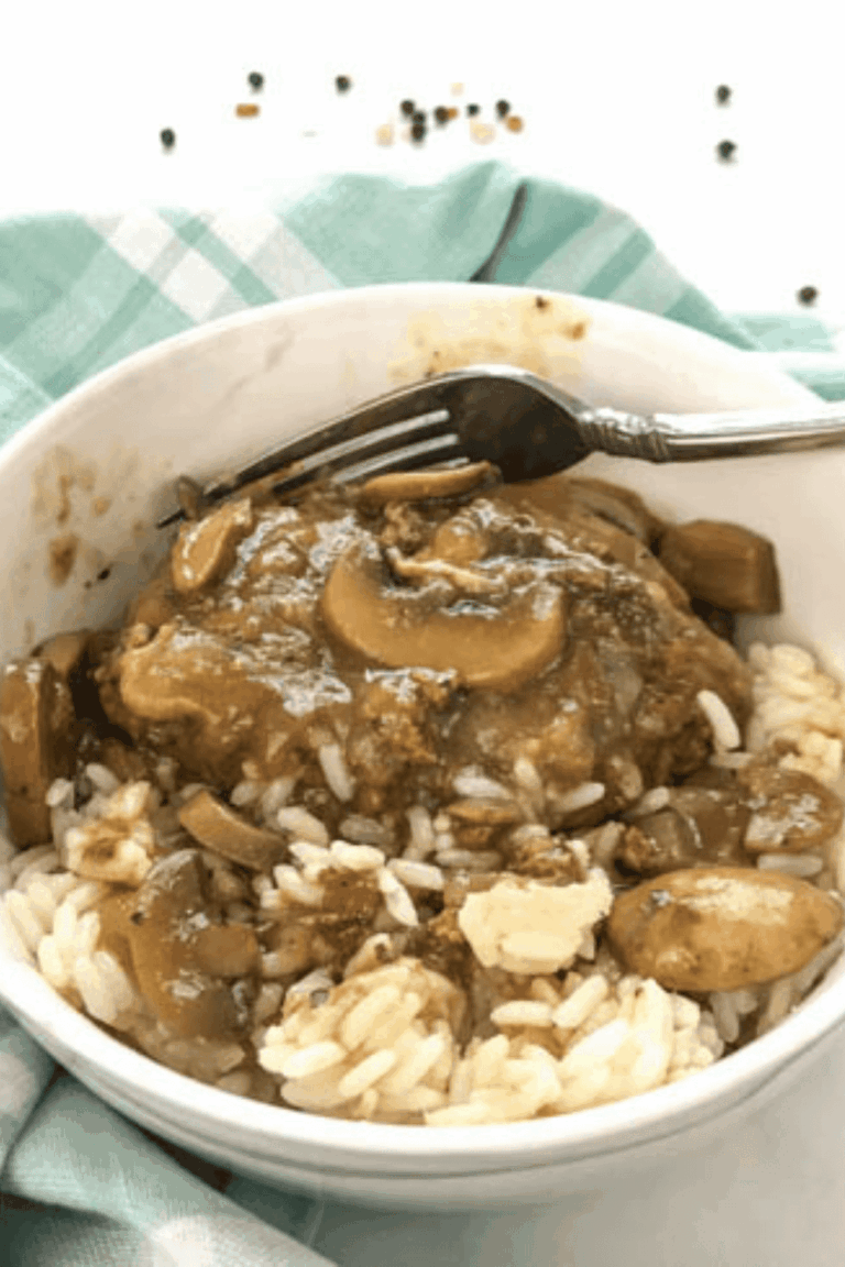 Salisbury steak in a white bowl with rice and a fork.