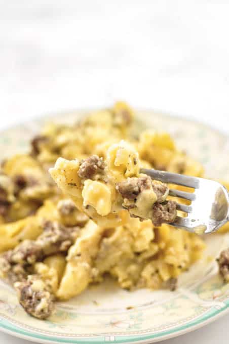 cheeseburger mac and cheese on a white plate and a fork with a bite. 