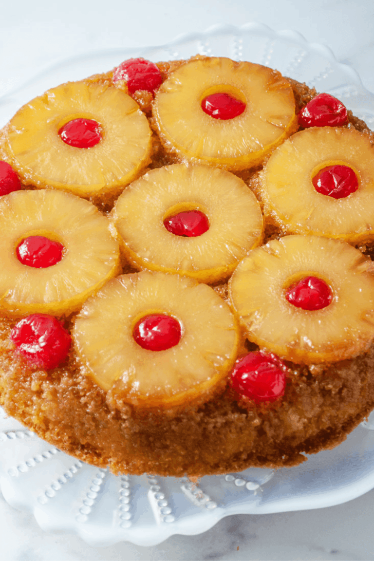 Classic pineapple upside down cake with caramelized pineapple slices and bright red cherries on a glass cake stand, an easy pineapple upside down cake recipe made with a moist pineapple cake and traditional upside down cake topping.
