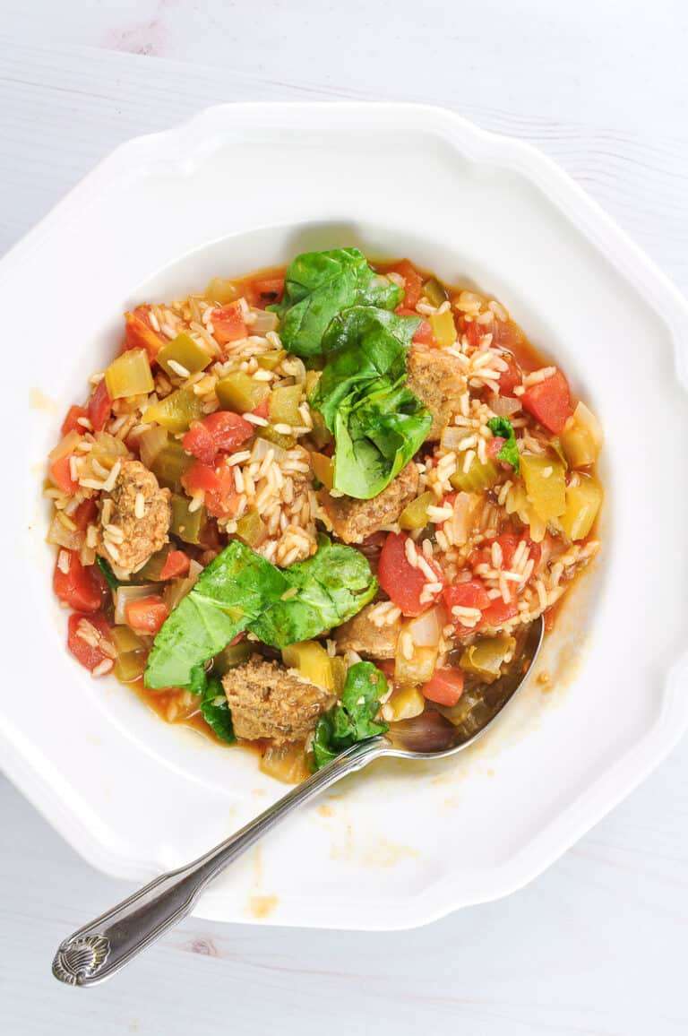 white bowl with silver spoon of vegetarian jambalaya on white counter
