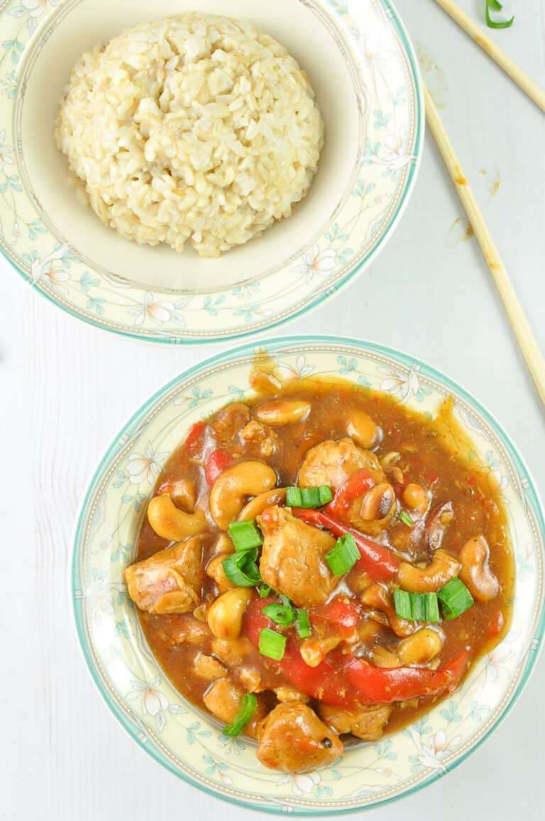Instant Pot Cashew Chicken in a flower and rim bowl with a second bowl of rice and two chopsticks Anna White counter.