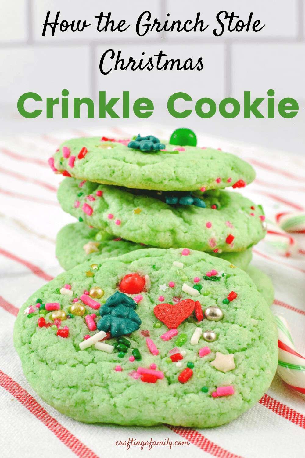 Easy grinch crinkle cookies decorate on with grinch sprinkles a stack of cookies on a white and red striped towel and candy canes on the towel.