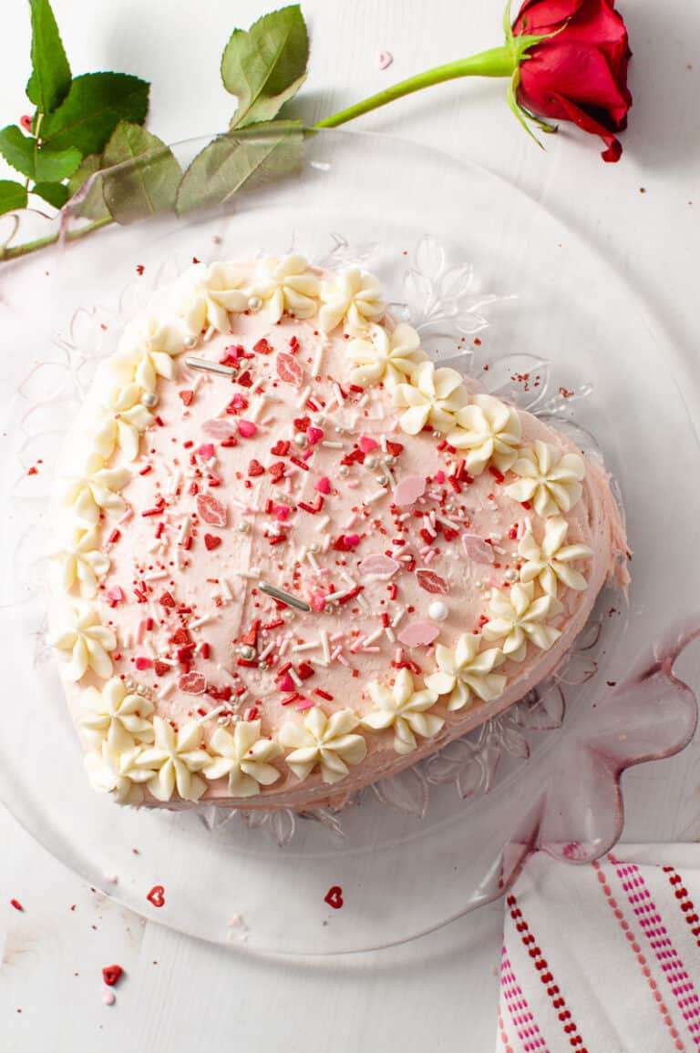 Easy Heart Shaped Red Velvet Cake top view of the heart cake and a red rose on the counter