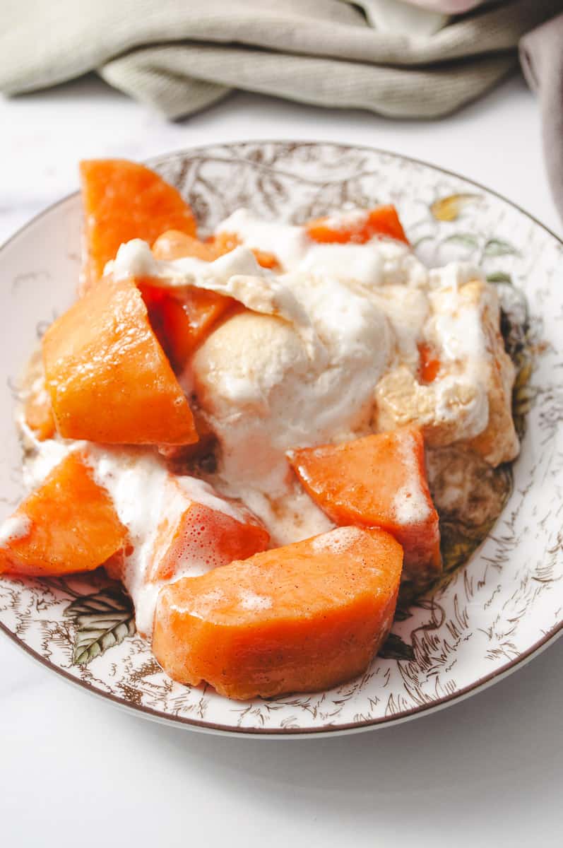 Candied sweet potato casserole on a Thanksgiving designed plate with chunks of sweet potato and gooey marshmallow melted on top.