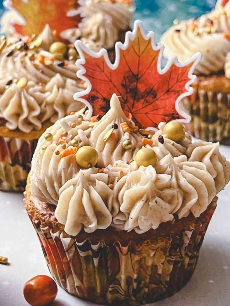 apple cider cupcake with frosting and a maple leaf topper