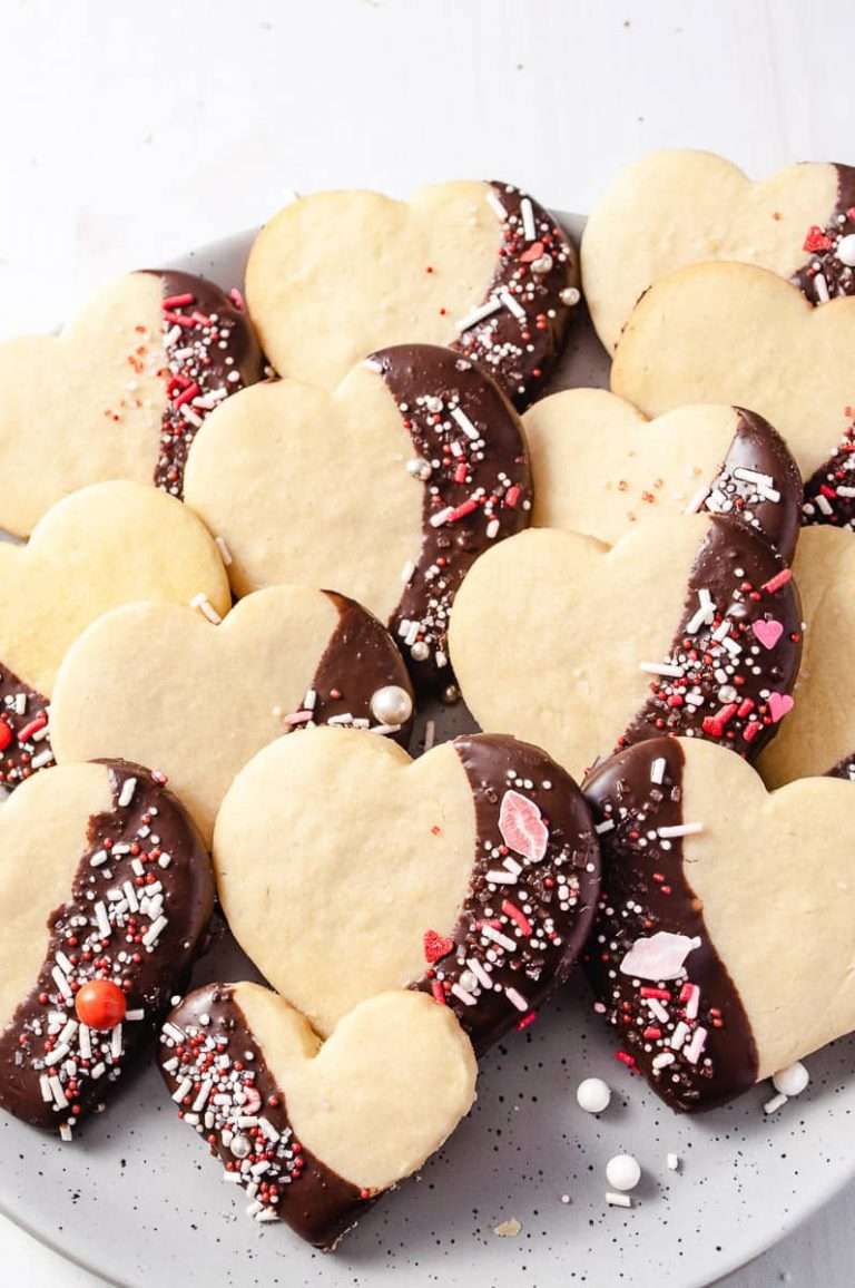 14 Valentine's Day Heart Shortbread Cookies Dipped In Chocolate with sprinkles and hearts and red lip sprinkles on a gray plate