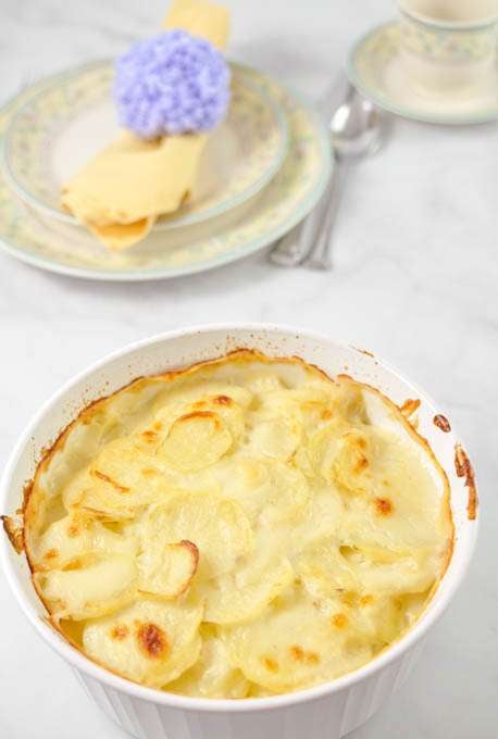 Baked scalloped potatoes casserole with tender sliced potatoes and a golden, creamy top, served in a white baking dish as a classic side dish.