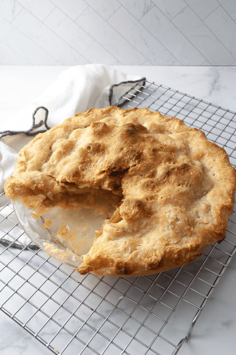 Rhubarb pie on a cooling rack on a white marble counter with a white with black trim towel