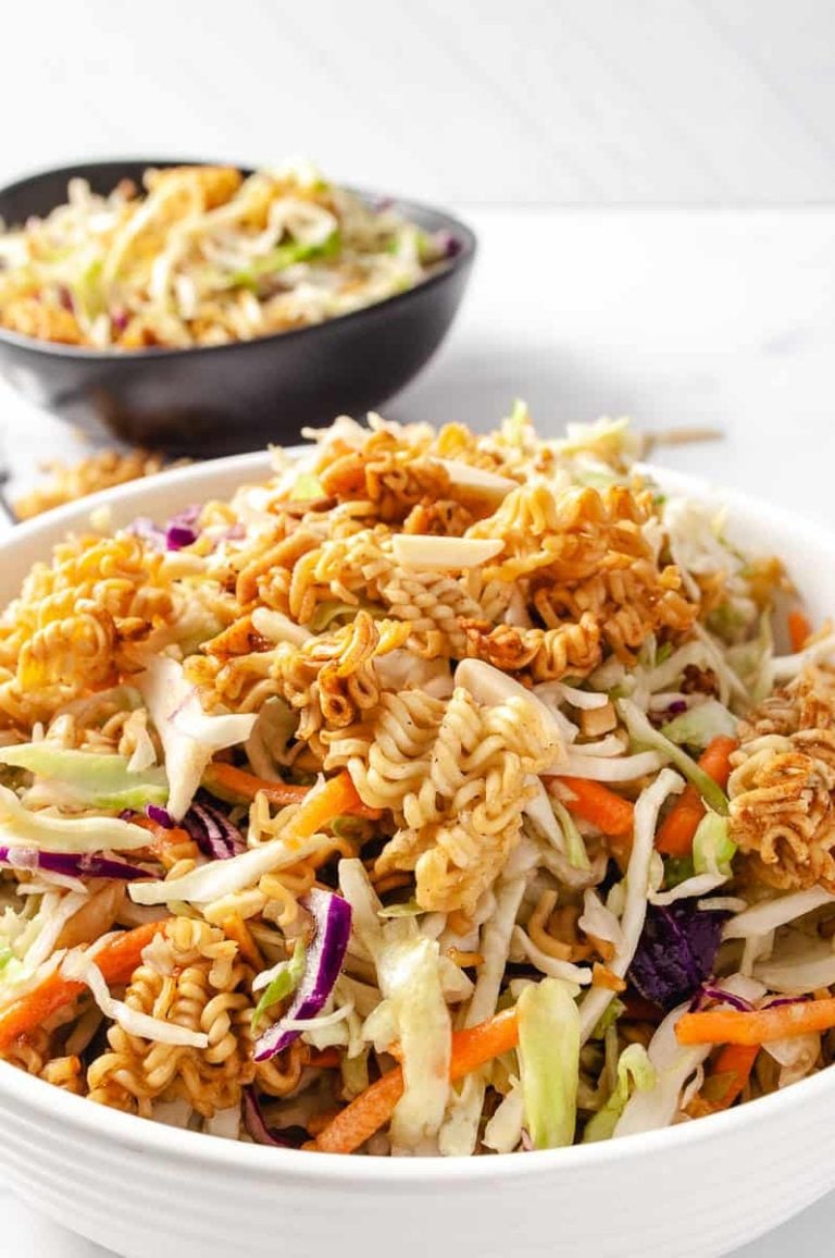 easy crunchy asian ramen noodles coleslaw salad in a white bowl on a white counter with a black small bowl in the upper left with a serving of the salad