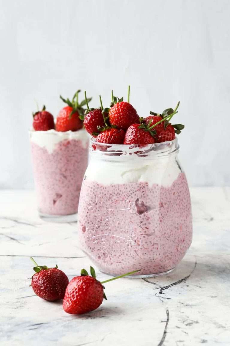 Fresh Strawberry Chia Seed Pudding Recipe with Almond Milk in a cup and dessert cup with whip topping and fresh strawberries on top 2 strawberries on counter