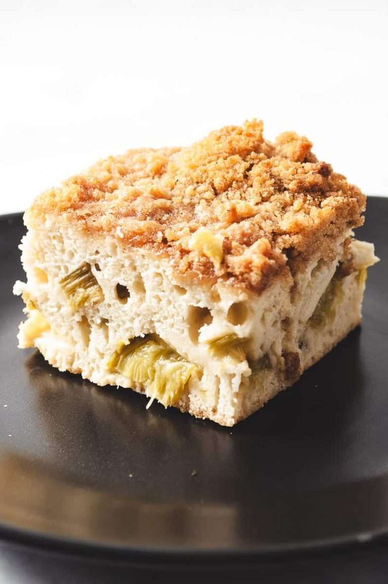 close up of a square of rhubarb coffee cake with streusel topping on a black plate