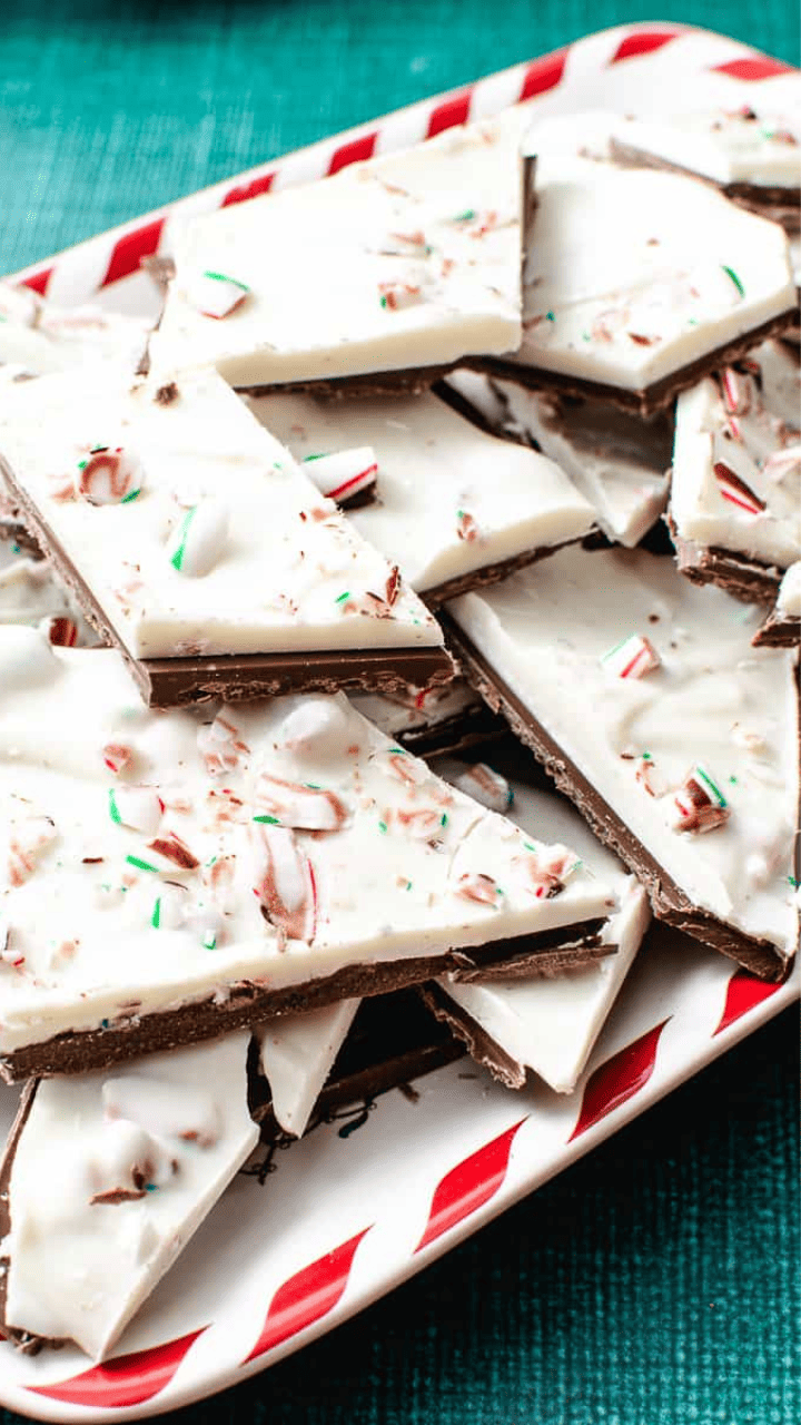 Easy Christmas Peppermint Bark all stacked up on itself in different shapes on a white plate with red strips. 