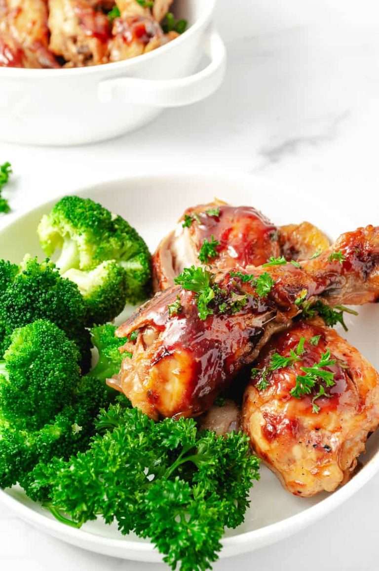 3 Ingredients BBQ Chicken Drumsticks CrockPot Recipe 3 drumsticks on a white plate with broccoli and parsley.