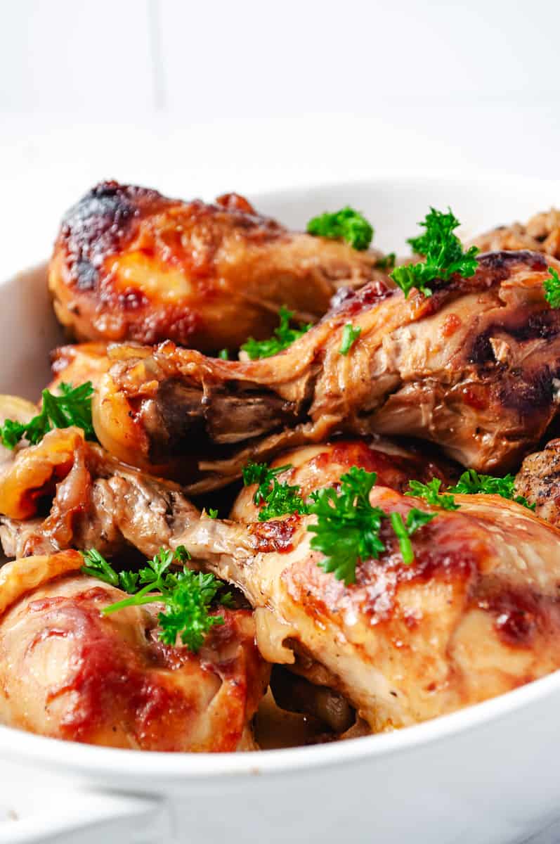 3 Ingredients BBQ Chicken Drumsticks CrockPot Recipe in a white serving bowl with parsley on
top 8 drumbsticks