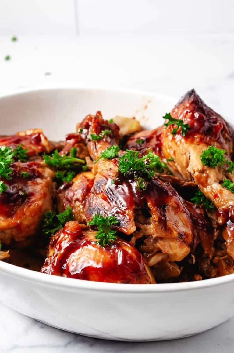 3 Ingredients BBQ Chicken Drumsticks CrockPot Recipe 8 drumsticks in a white serving dish with parsley on top.