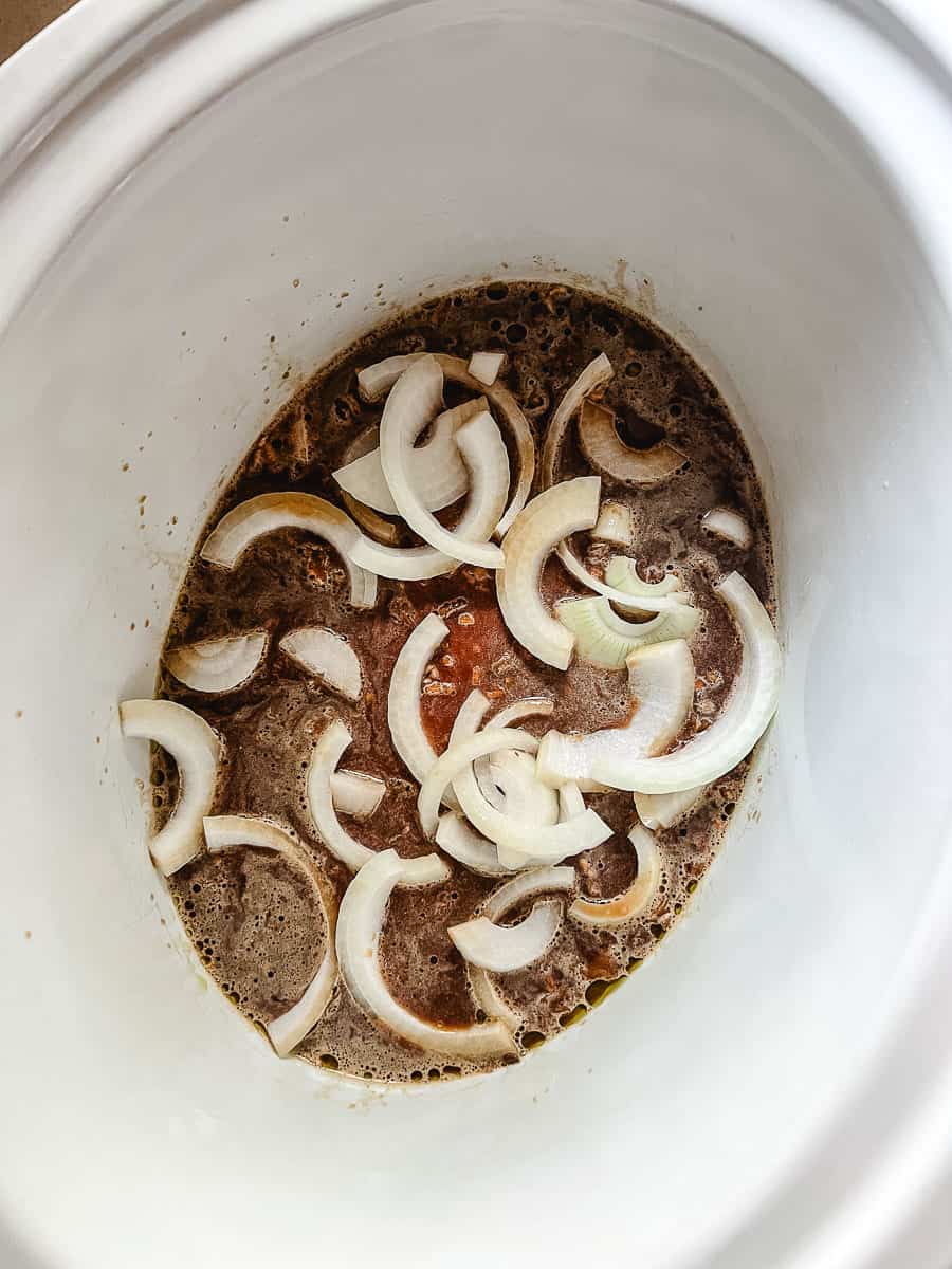 Irresistibly Tender CrockPot Cube Steak with Gravy onion at the bottom of the crcokpot.