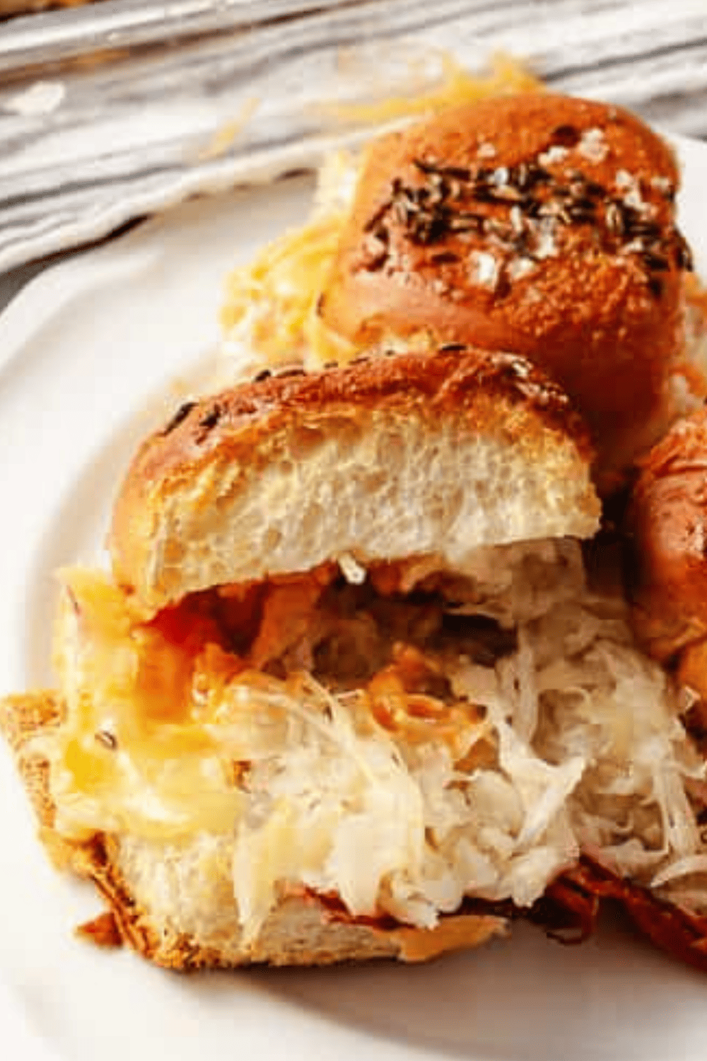 Reuben Sliders Sandwiches: Perfect Party Appetizer close up of 2 slider sandwiches on a white plate.