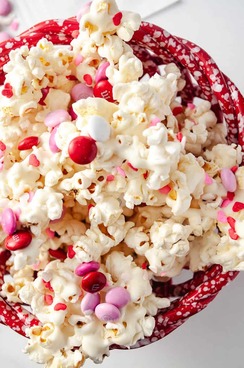 Easy Valentine's White Chocolate M&M Popcorn Treat top view and close up of the popcorn with white chocolate drizzle and m&ms and sprinkles