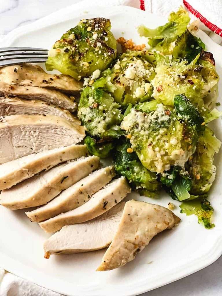 Tender Crispy Super Easy Air Fryer Chicken Breast on a white plate with brussels sprouts.