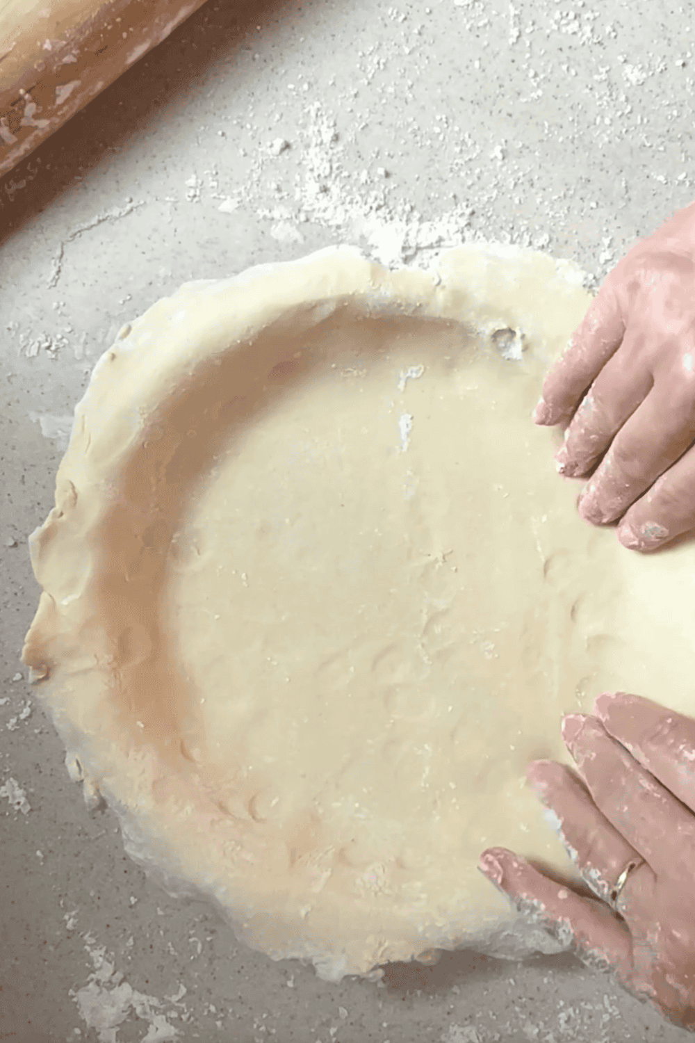 Perfect Flaky Pie Crust Without a Food Processor close up of the dough in the pan and hands shaping.