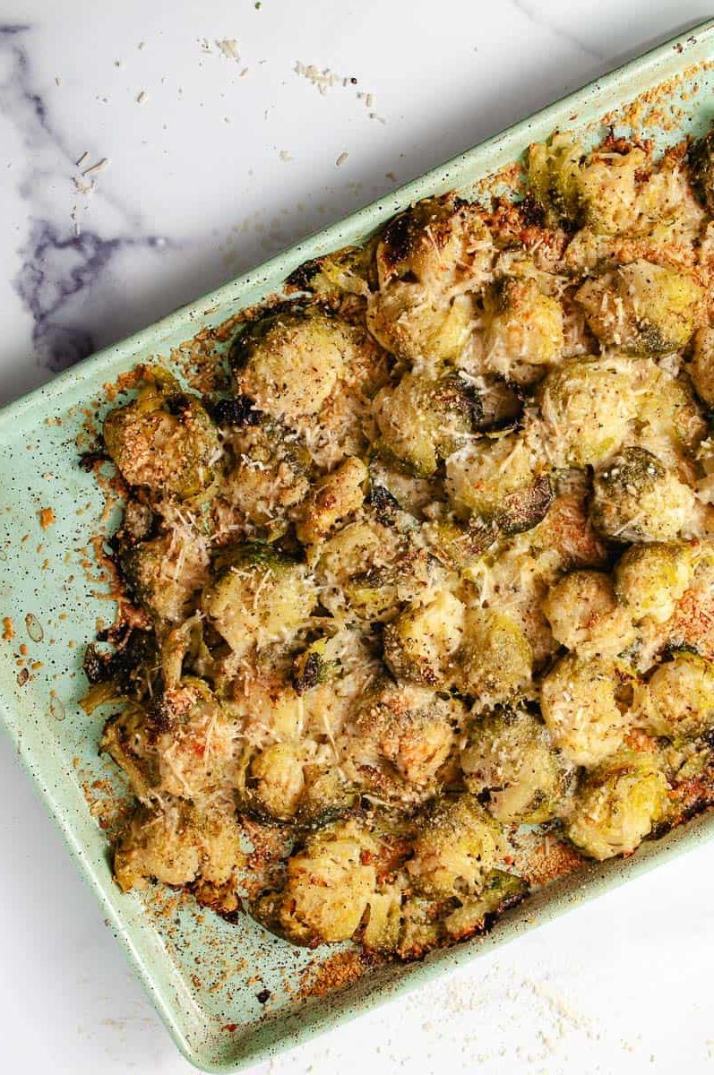 Easy Crispy Parmesan Smashed Brussels Sprouts, baked golden brown crispy finished on a green baking sheet.