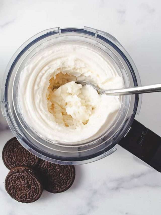 ninja creami pint with vanilla ice cream delicious and creamy with a spoon with 3 oreos on the counter and a spoon in the pint.