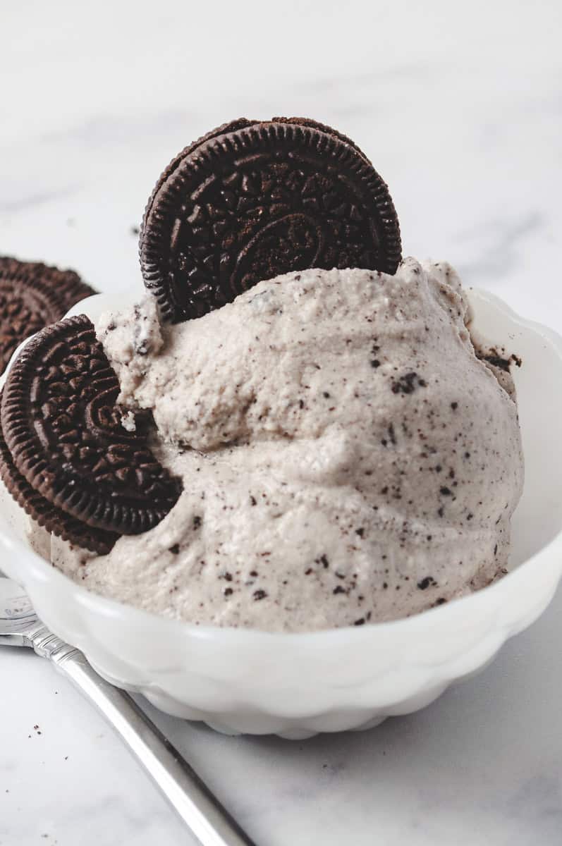 ninja creami cookies and cream in a white bowl with 2 oreos in the ice cream and oreos on the counter