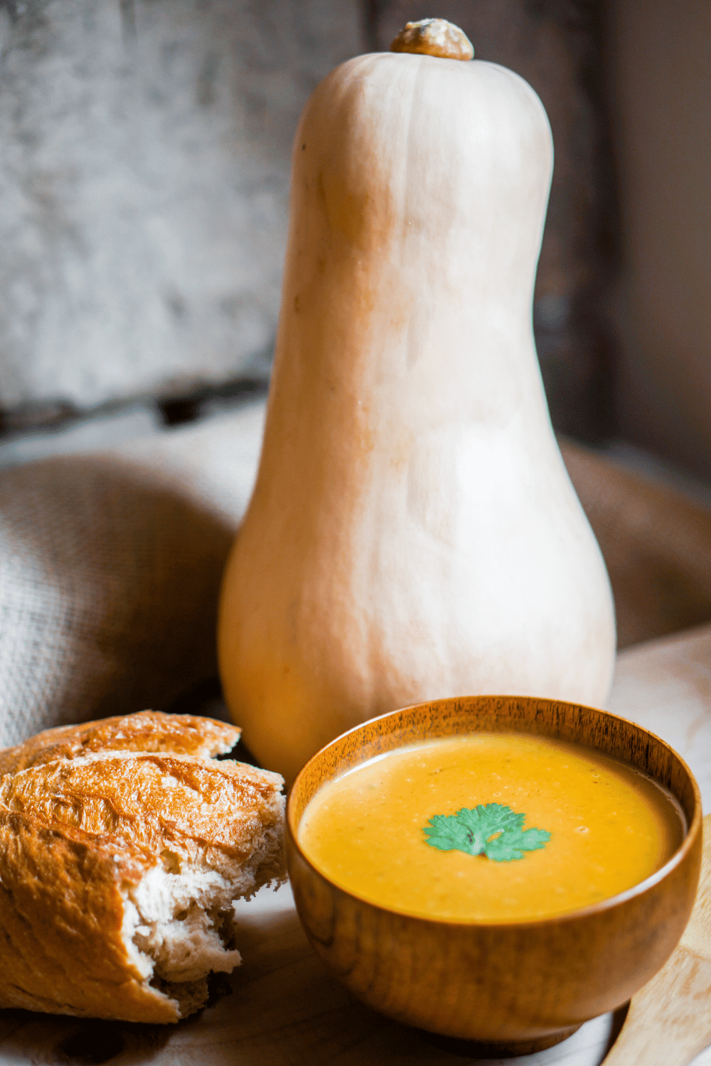 butternut squash soup with a whole butternut squash and crusty bread on the table.
