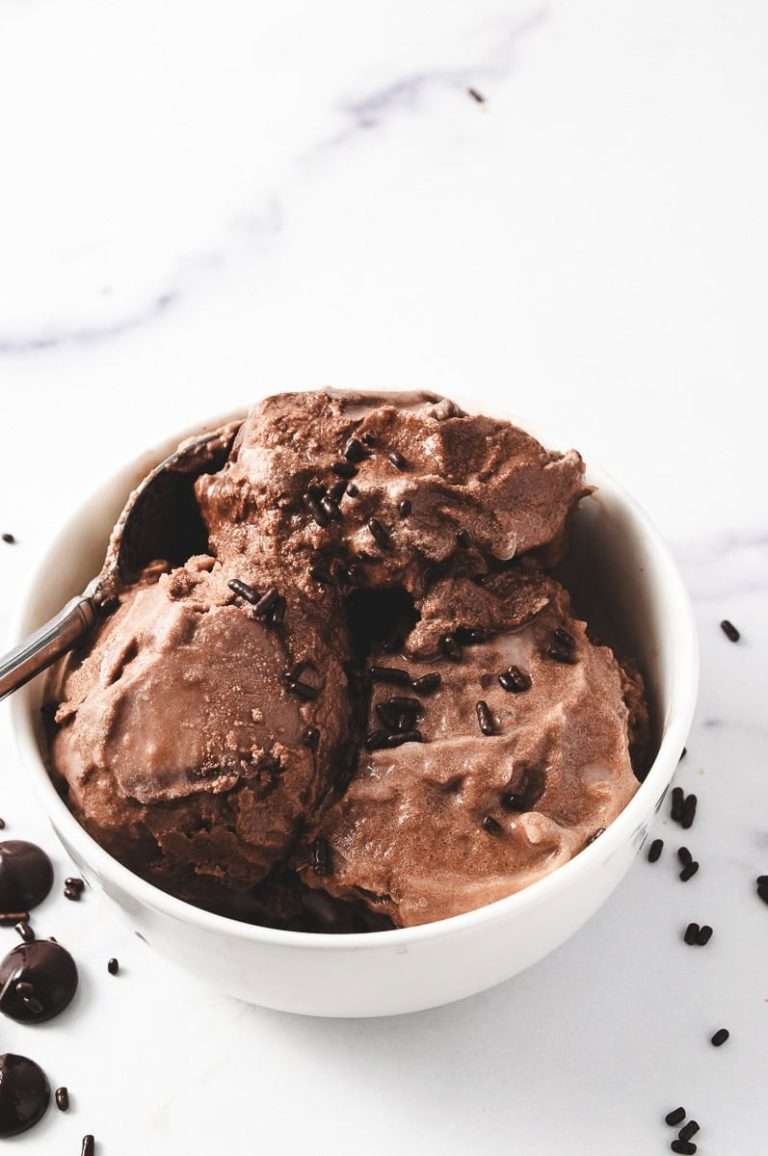 Ninja Creami Chocolate Ice Cream-Special Dark Cocoa 3 scoops in a white round bowl on a white counter with chocolate sprinkles and chocolate chips on the counter.