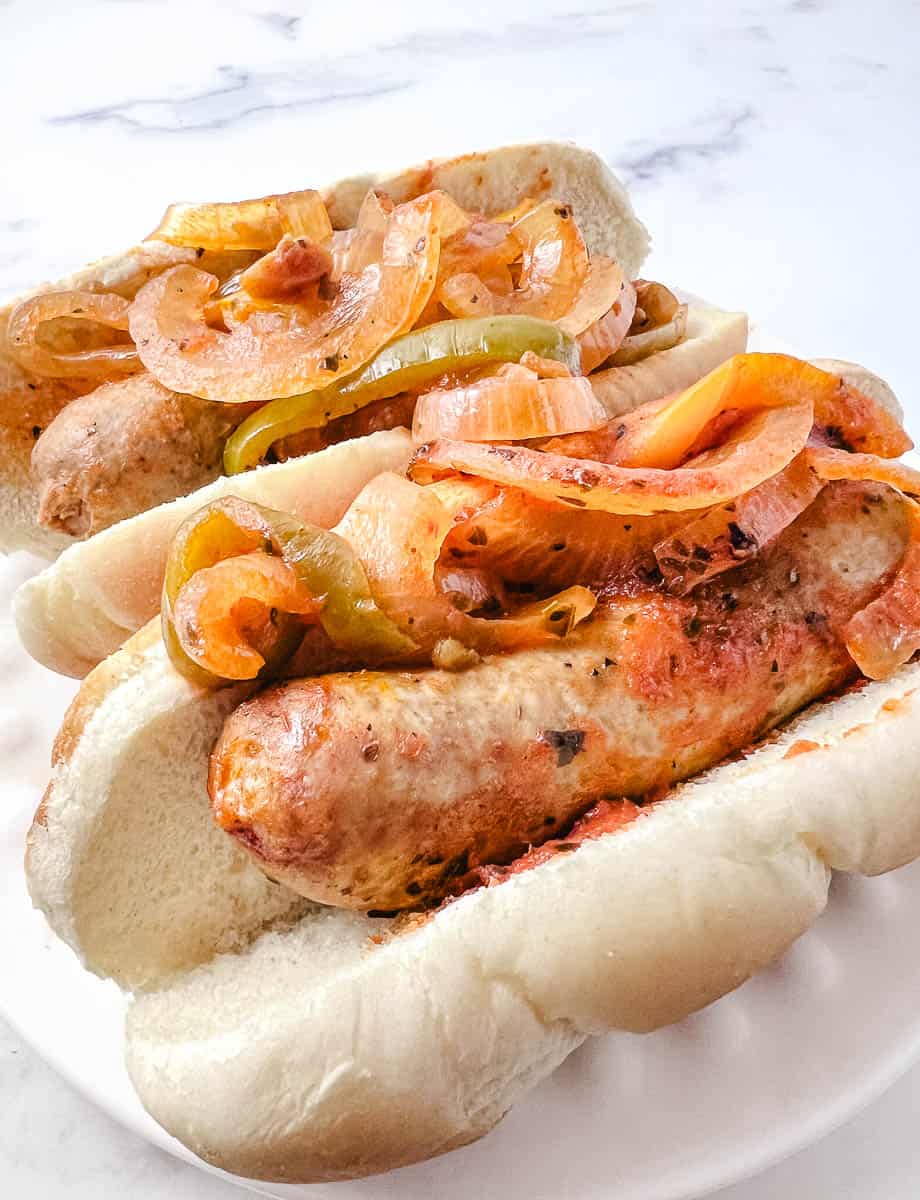 Easy CrockPot Italian Sausages Peppers Onions 2 in buns on a white counter
