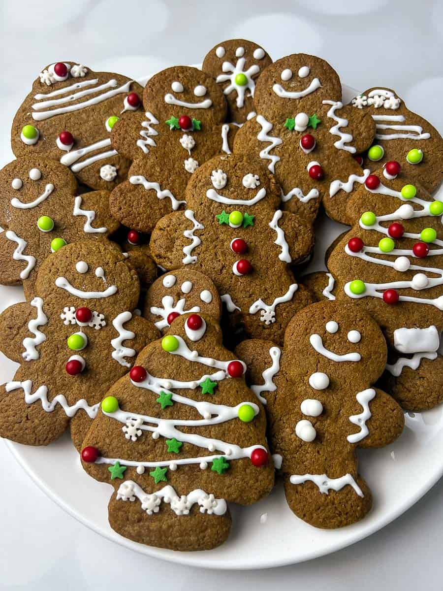 Plate of soft gingerbread men cookies decorated with white icing, red and green candy buttons, and festive designs, perfect for Christmas cookies, holiday baking, and cookie exchanges.