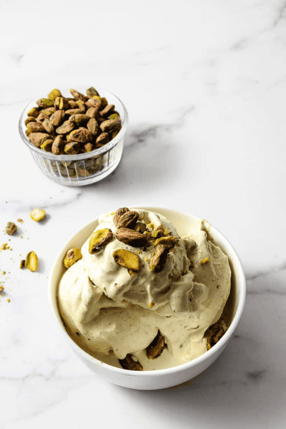 St. Patrick's Day Pistachio Ice Cream Ninja Creami Recipe in a whit bowl with crushed pistachios on the table.