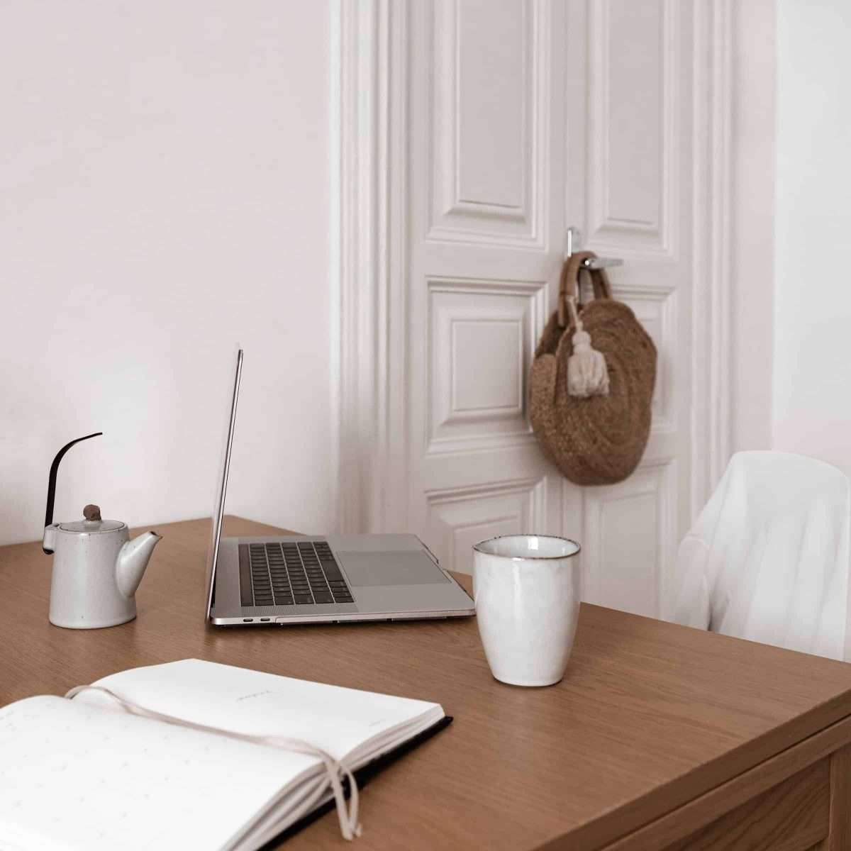 Using the Envelope System: A Beginner’s Budgeting Guide yeah college wrong with the computer tea cup and tea pot and journaling book a price on a door and a white shirt on a chair.
