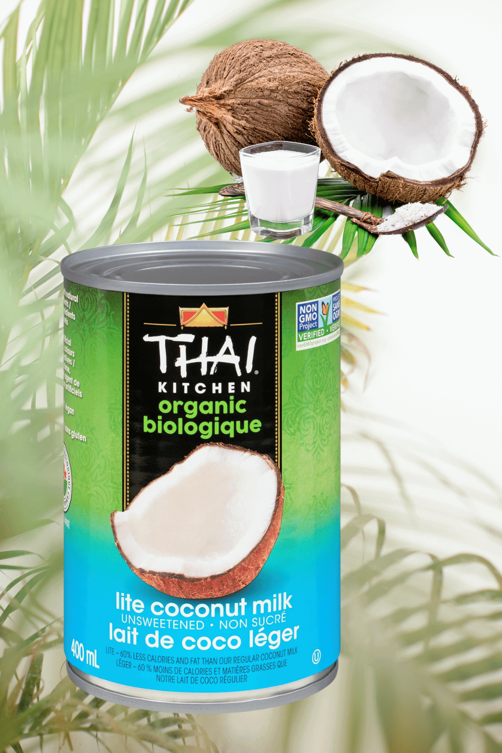 a can of coconut milk and 2 coconuts and a glass of coconut milk in the top right with a palm leaf background