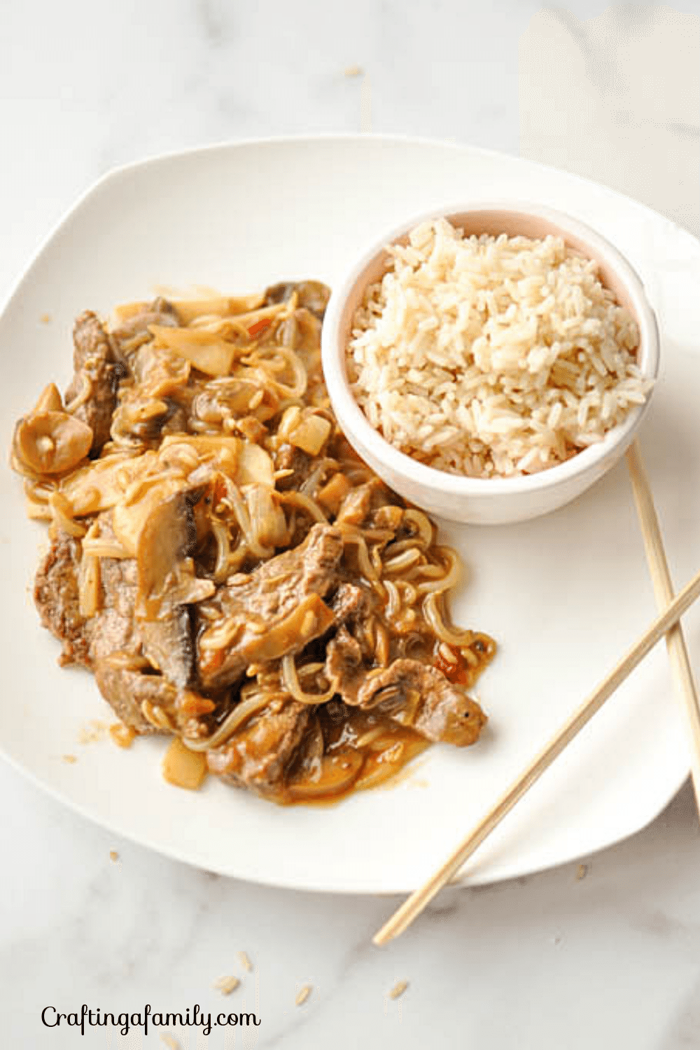 Easy Japanese Beef and Vegetable Sukiyaki Stir Fry on a white square plate with a white bowl of rice and 2 chop sticks.