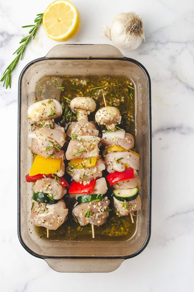 Raw chicken skewers marinating in a herb and garlic mixture with chunks of zucchini, bell peppers, onions, and mushrooms—ideal for grilled chicken skewers and flavorful chicken skewer recipes. A great prep step for kabobs on the grill chicken, perfect for quick weeknight meals using a delicious skewer marinade.