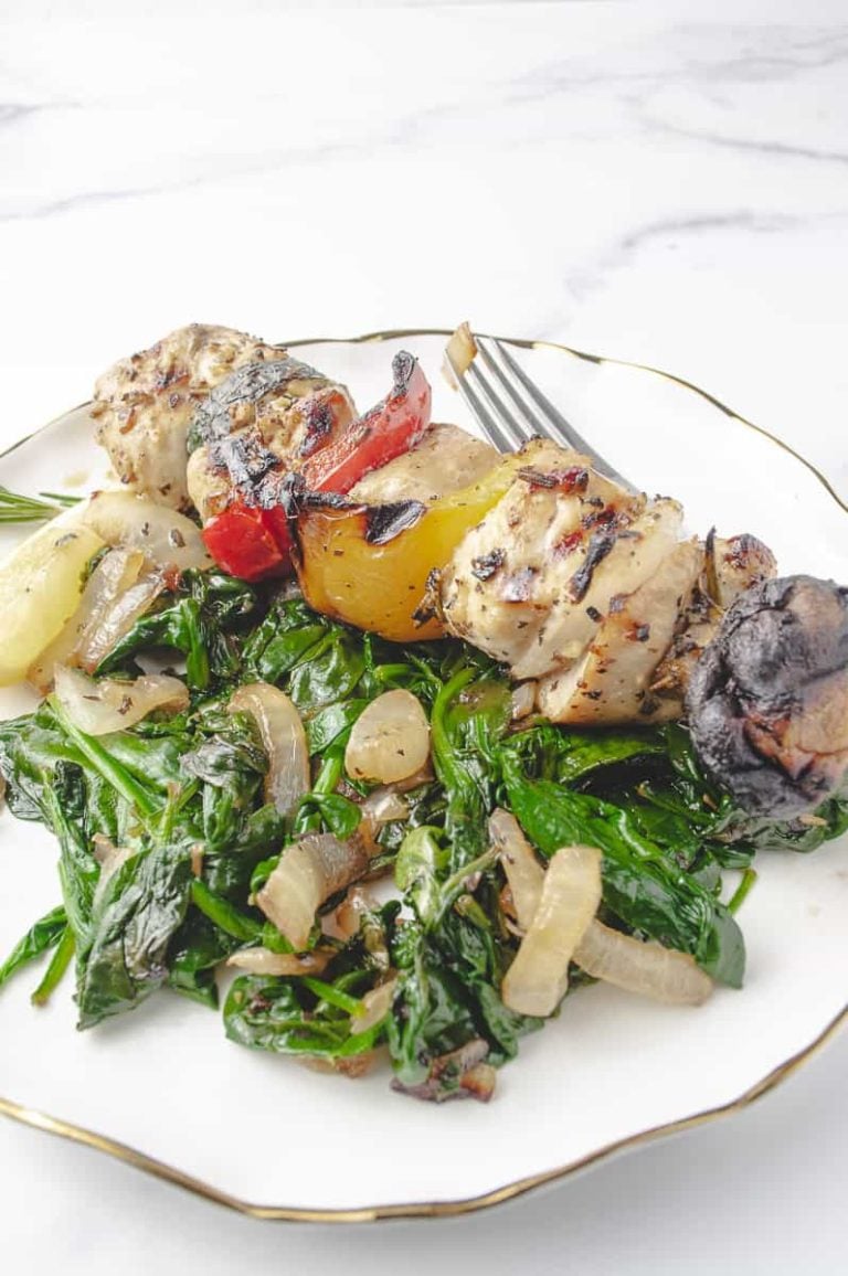 Flavorful chicken skewers served with sautéed spinach and caramelized onions on a white plate—featuring grilled vegetables and tender chicken pieces. A tasty option for grilled chicken skewers, this hearty chicken skewer recipe is a standout among skewer recipes and perfect for cooking on the skewers grill or making chicken skewers on the grill for a balanced meal.