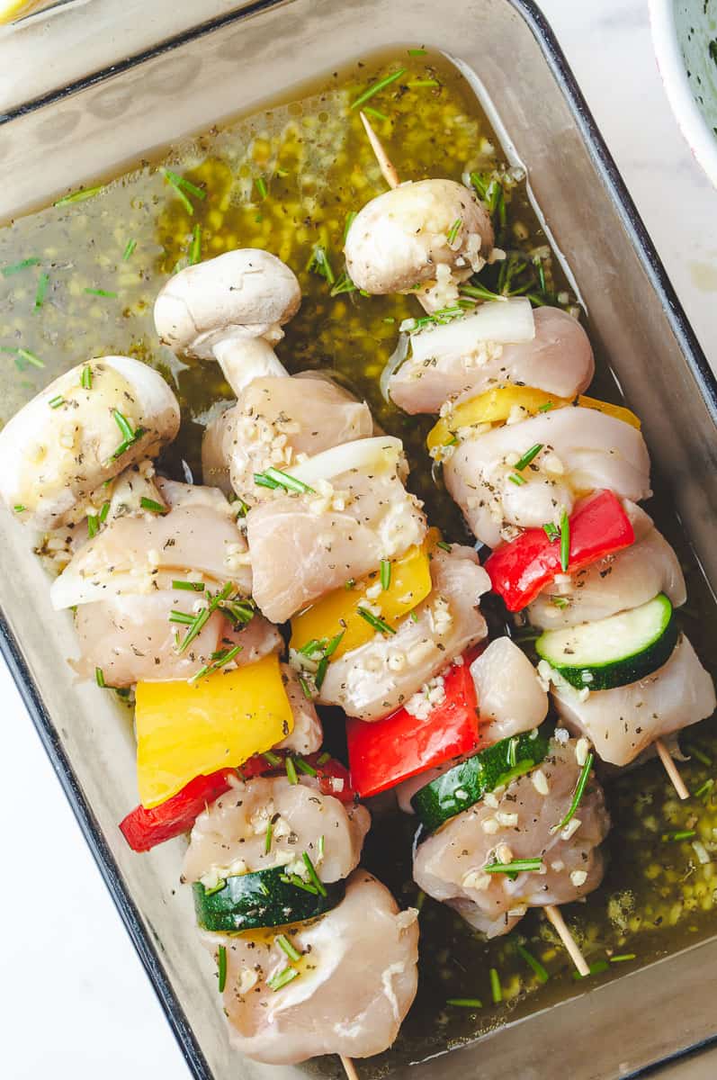 Close-up of raw chicken skewers in a flavorful skewer marinade with garlic, rosemary, and olive oil, featuring colorful vegetables like zucchini, bell peppers, onions, and mushrooms—ideal for grilled chicken skewers and perfect for easy chicken skewer recipes and quick weeknight meals on the skewers grill.