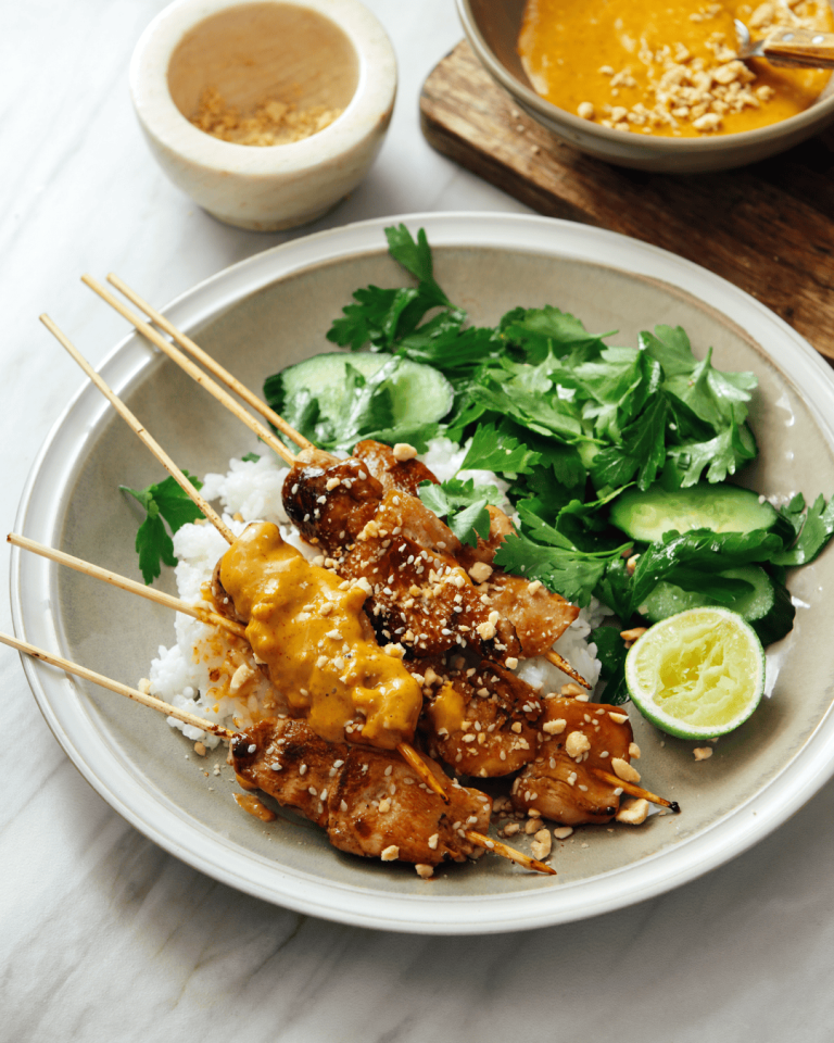 Grilled skewers of juicy Thai peanut chicken served over rice with fresh cucumber, herbs, lime, and creamy peanut sauce chicken drizzled on top. This flavorful bowl brings together classic Thai chicken recipes with bold peanut chicken flavor, perfect for a healthy and vibrant dinner.