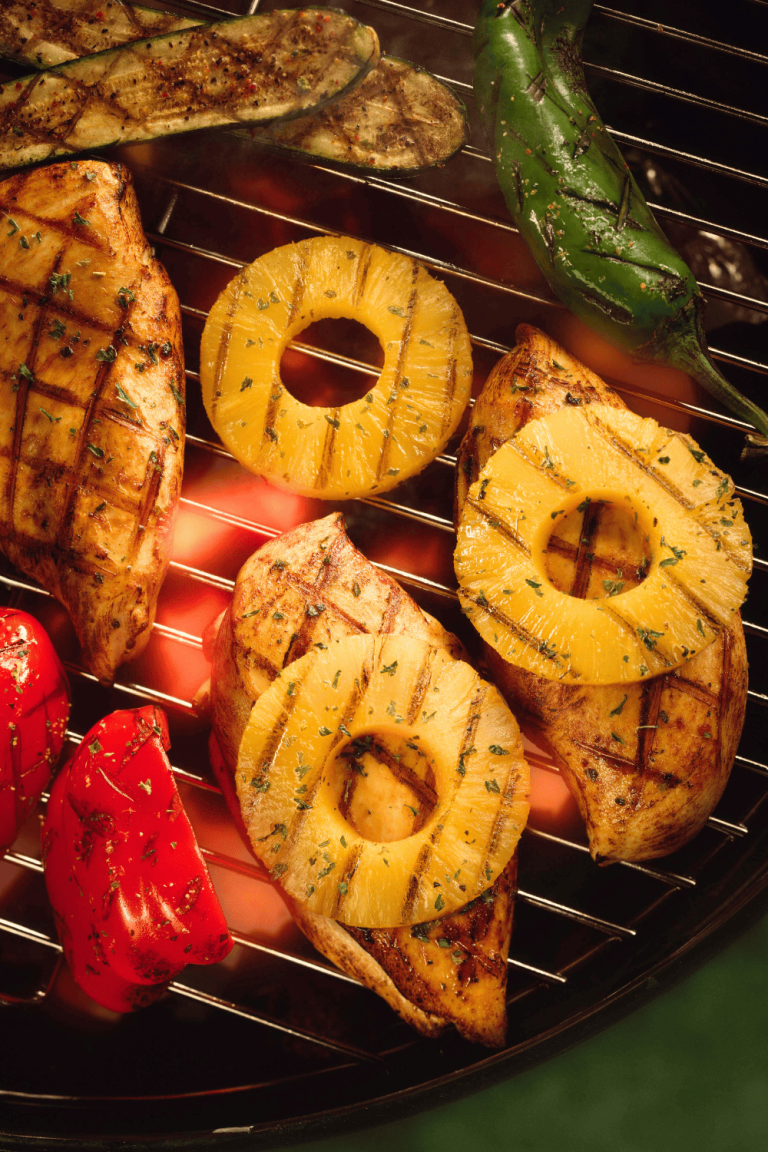 Grilled chicken breasts topped with juicy pineapple rings on a hot grill, surrounded by charred vegetables, all infused with a sweet and savory pineapple teriyaki chicken flavor. This tropical-style pineapple marinade for chicken brings bold, juicy flavor to every bite, perfect for your next grilled teriyaki chicken or summer cookout with a tangy teriyaki marinade twist.