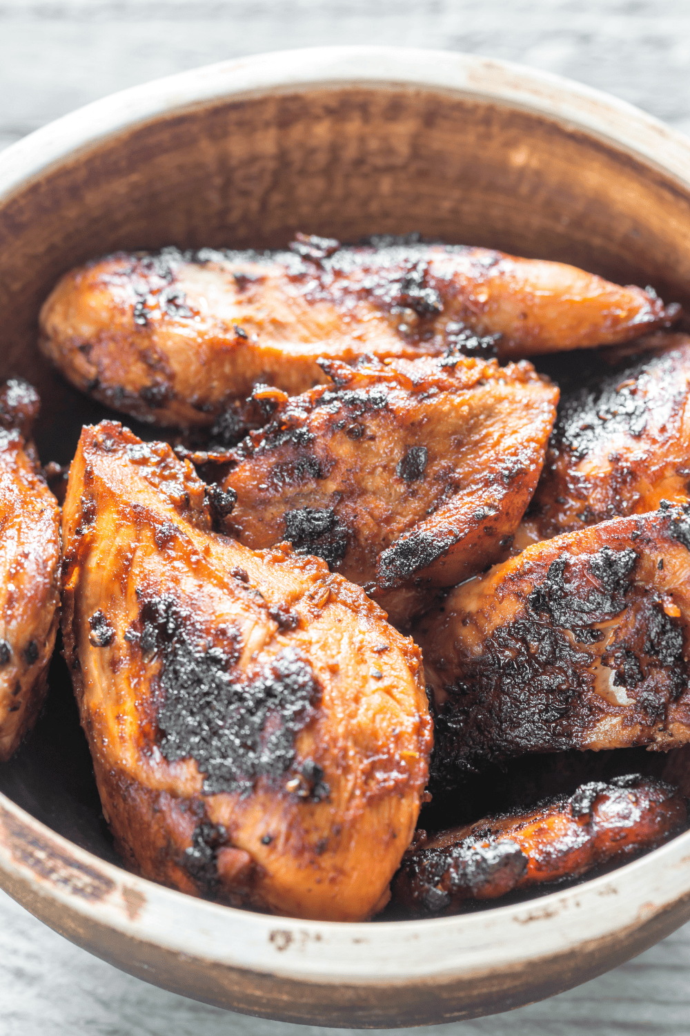 Close-up of juicy grilled chicken in a wooden bowl, coated in a smoky chipotle chicken marinade with charred edges for extra flavor. This bold and spicy chipotle chicken recipe uses a rich chipotle marinade for chicken, perfect for fans of fiery chipotle pepper recipes and grilled Southwest-style dinners.
