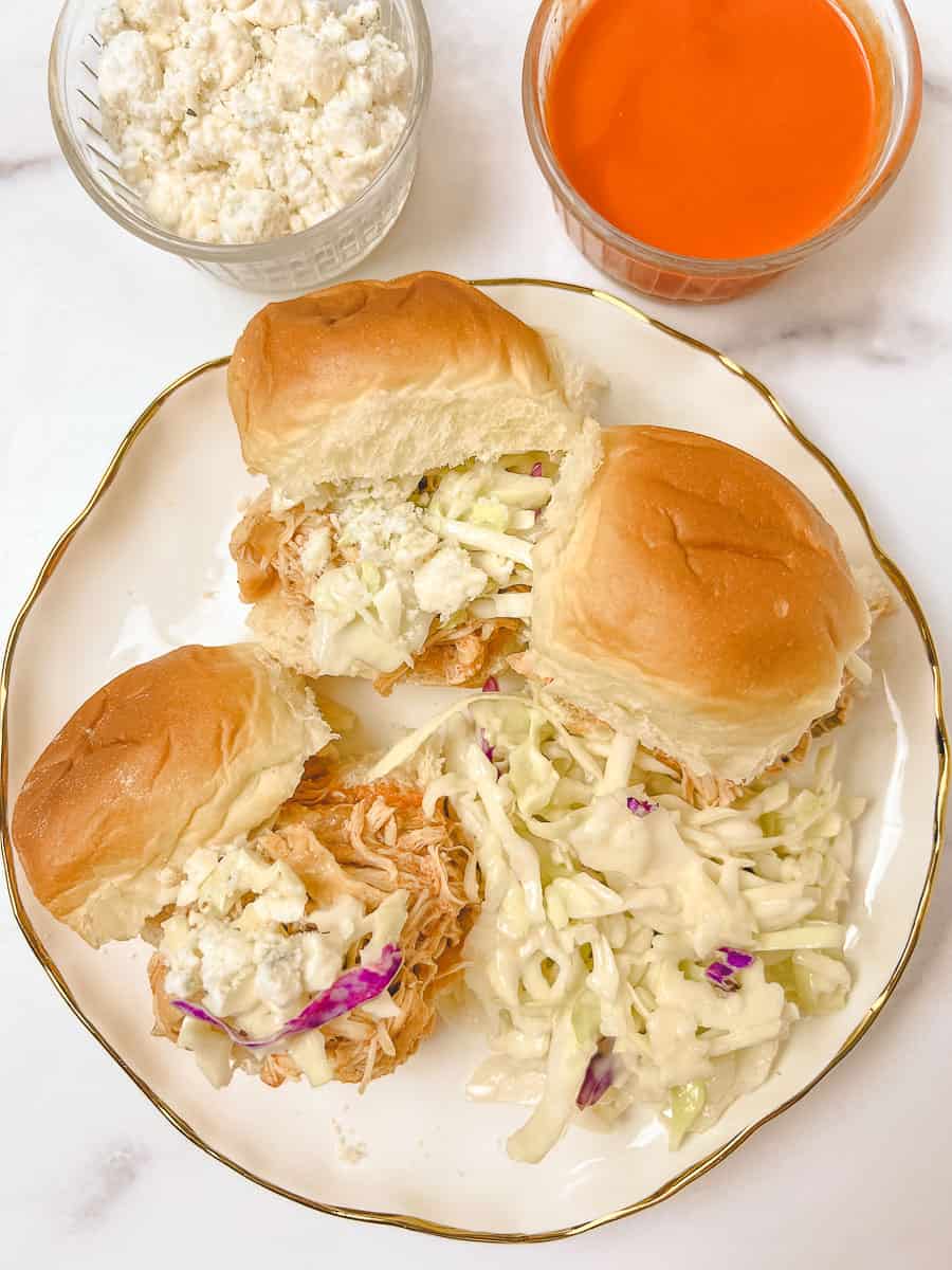 Irresistible Buffalo Chicken Sliders, fresh from a Crockpot Buffalo Chicken recipe! Soft slider buns are piled high with spicy Shredded Buffalo Chicken, drizzled with extra Buffalo sauce, and topped with creamy blue cheese crumbles and crunchy coleslaw. A side of vibrant Buffalo sauce is ready for dipping, making these Slow Cooker Buffalo Chicken Sliders a game-day favorite. 