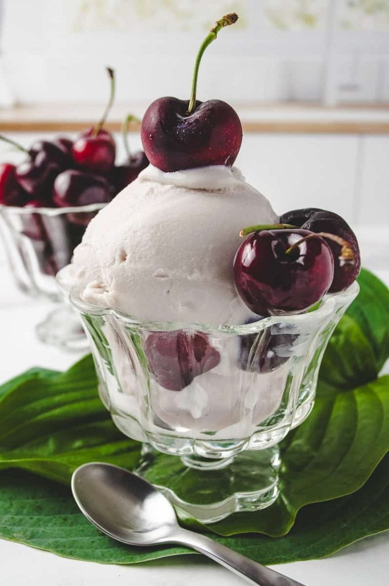 Glass dish filled with creamy Cherry Frozen Yogurt topped with whole cherries, perfect for a Cherry Ninja Creami dessert. This Frozen Yogurt Recipe uses the Ninja Creami Frozen Yogurt Recipe method with frozen cherries for a rich, smooth texture. A healthy twist on Frozen Cherry Recipes for summer, great for those looking for Frozen Cherry Recipes Healthy ideas.